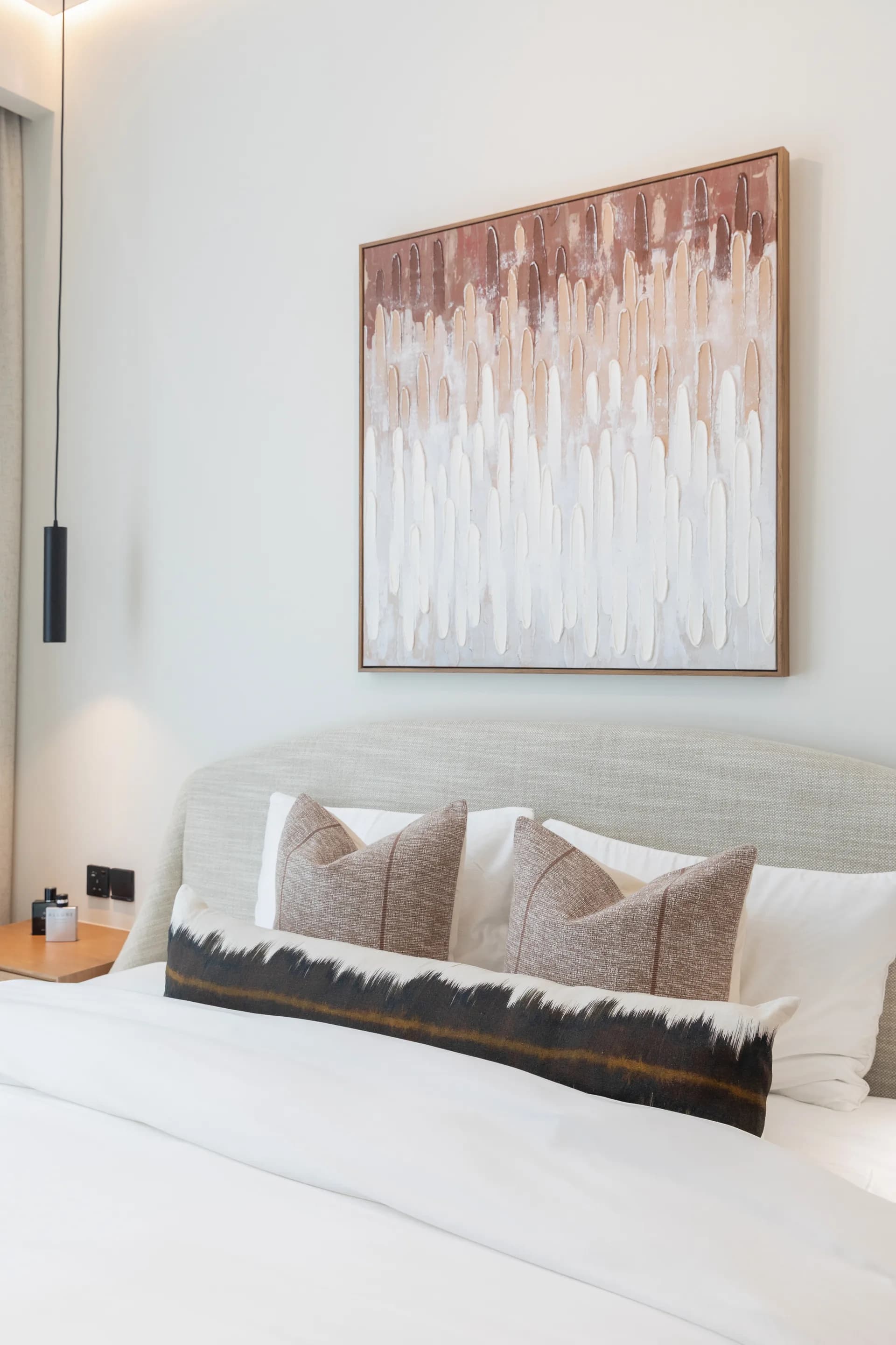 Bedroom with a soft upholstered headboard and a large abstract canvas in rose and white